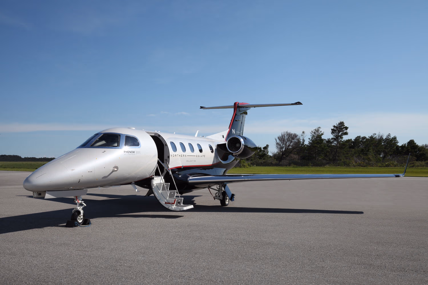 Phenom 300E parked at an FBO with airstairs deployed